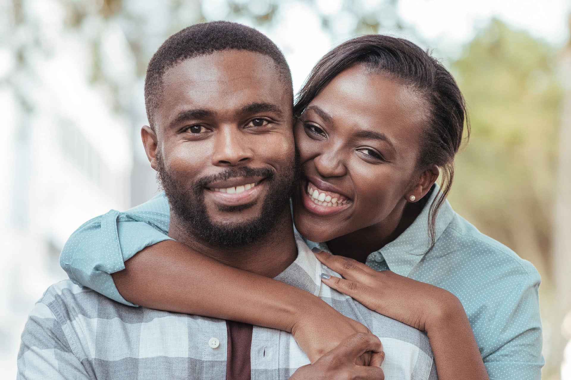 african american couple hugging and smiling at the camera in the park