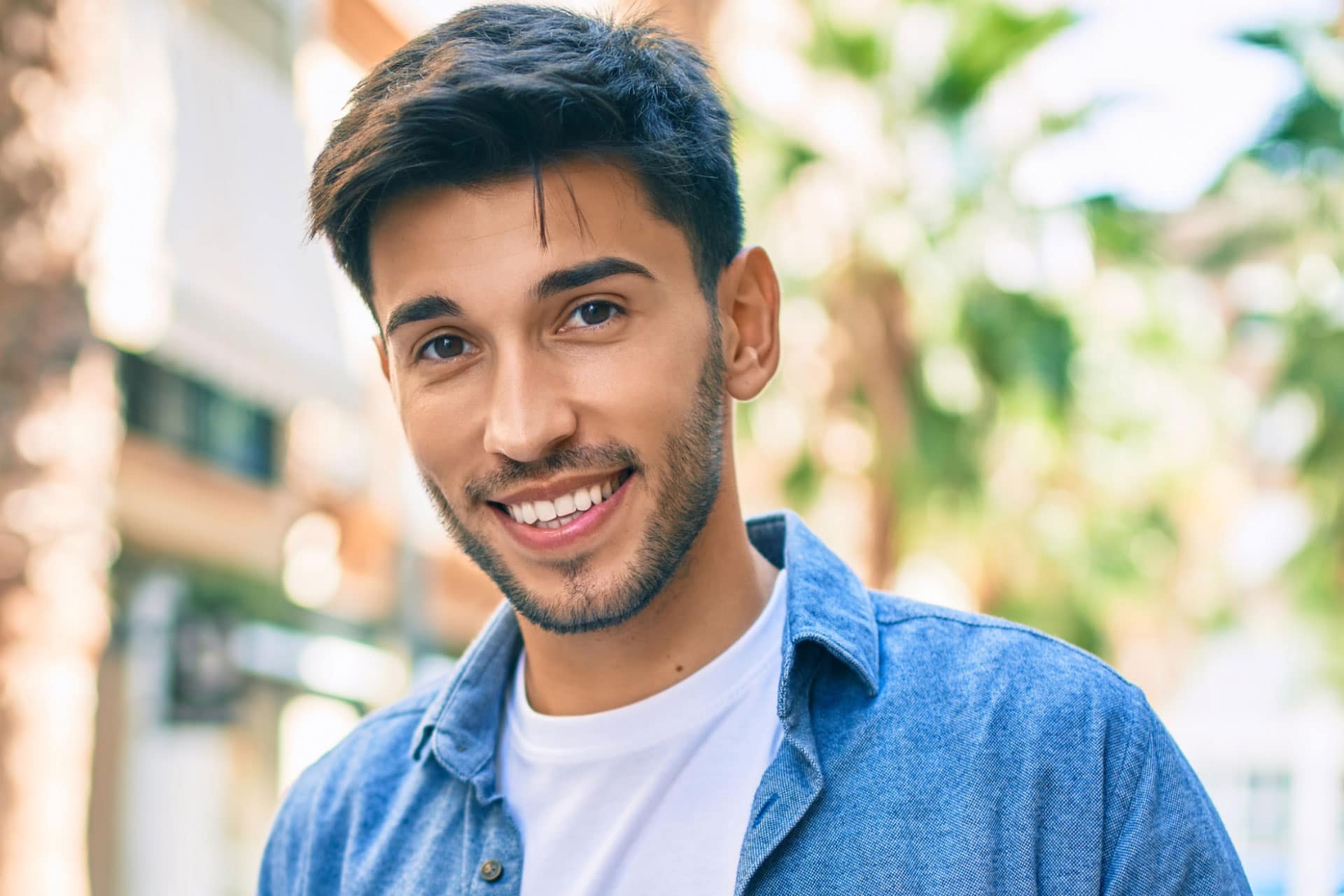 Young latin man smiling at the camera while walking at the city.