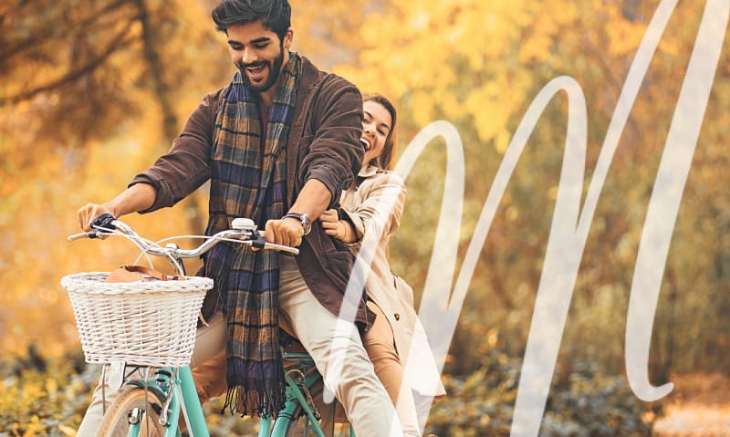 man rides a woman's bike with a woman on the back. both are laughing.