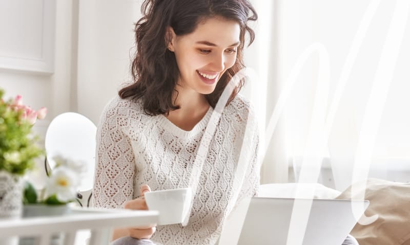 woman drinks her coffee with learning about endodontics on her laptop. everything in the room is white