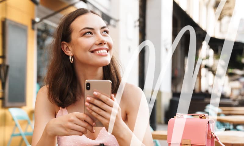 woman looks up from her phone and smiles