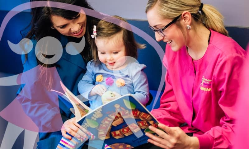 team member reads to small patient and mom