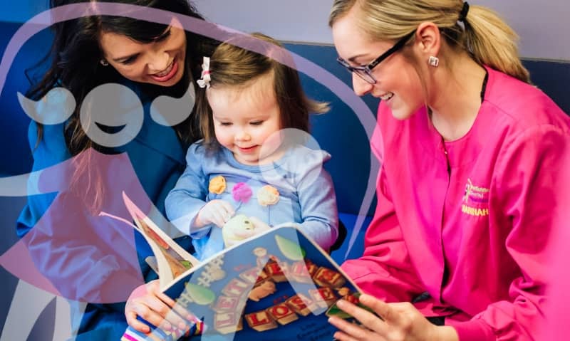 team member reading with young patient in chair