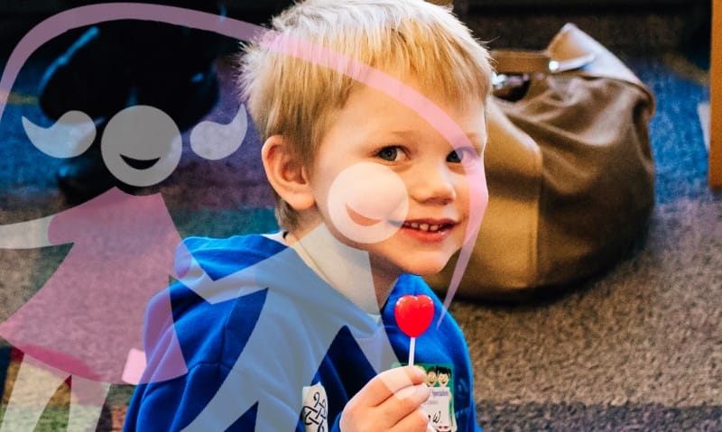 young guy with a red, heart shaped lollypop
