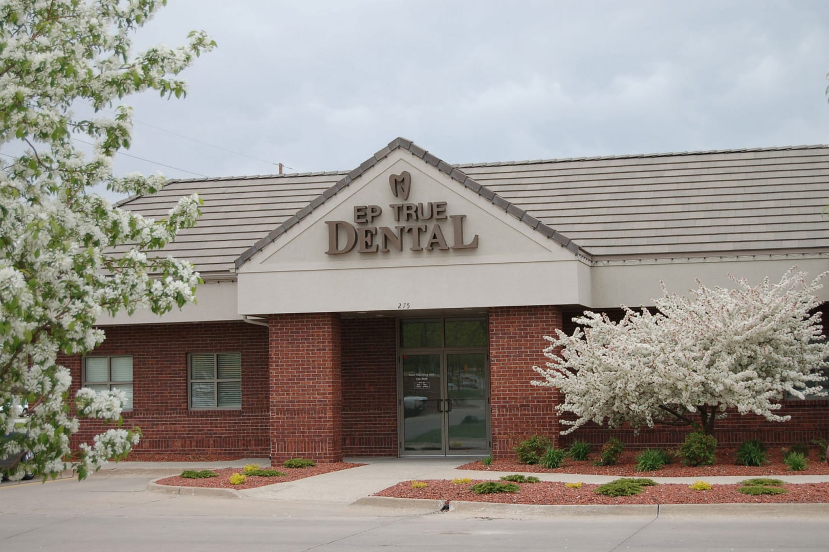 EP True Dental office building exterior with trees blooming white flowers