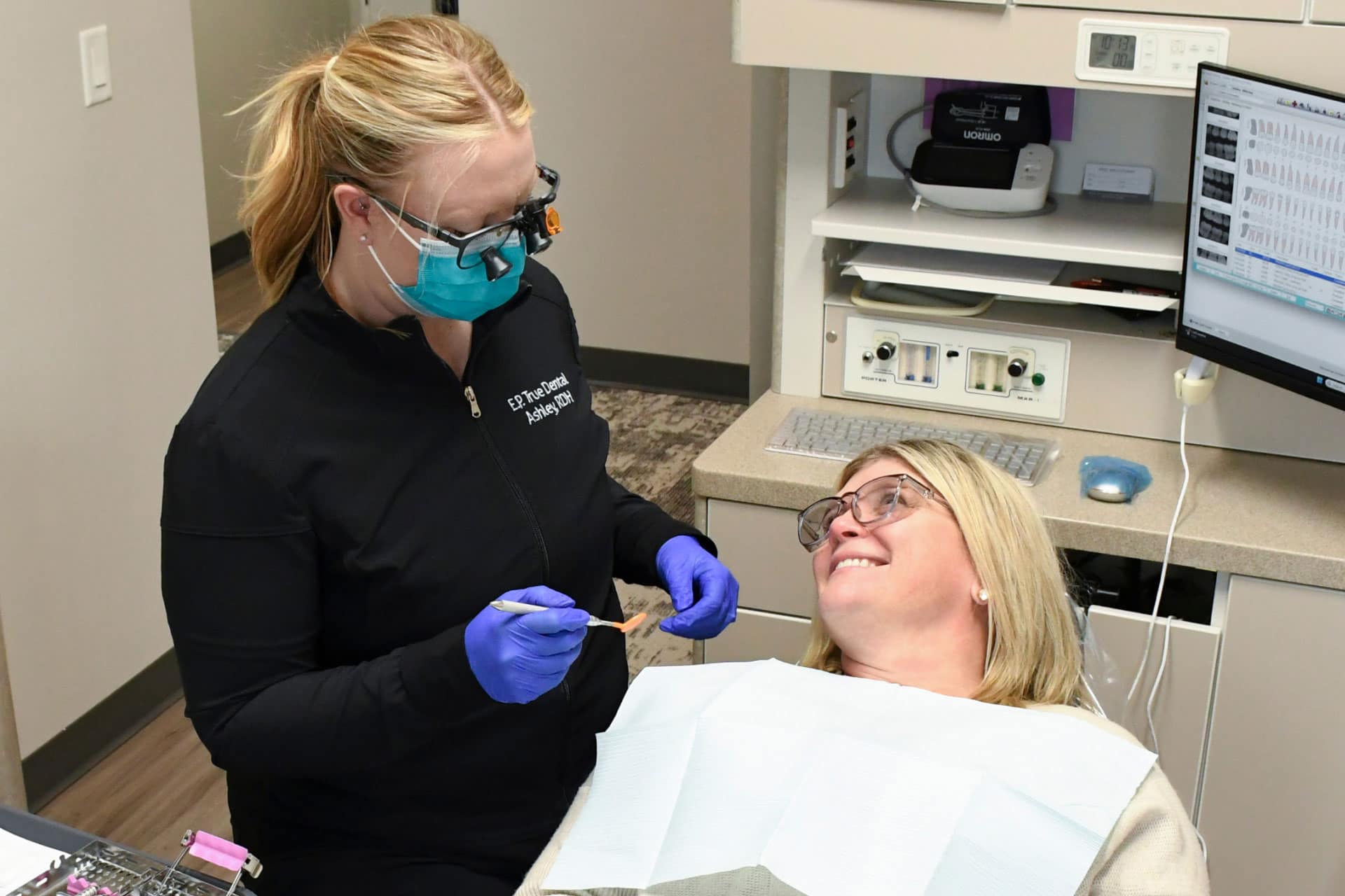 dental hygienist with patient in exam room