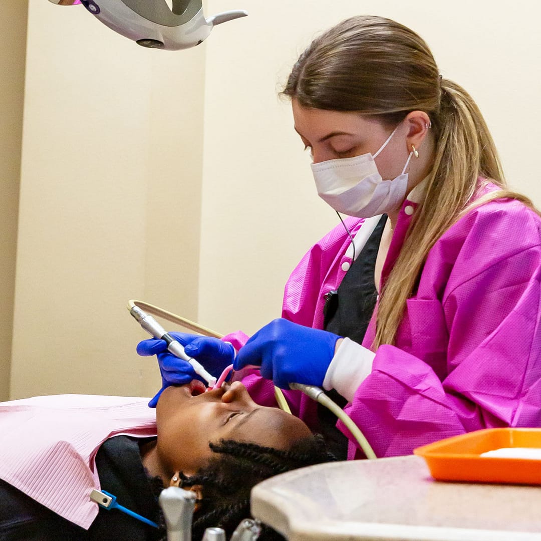 team member with pediatric patient in exam room