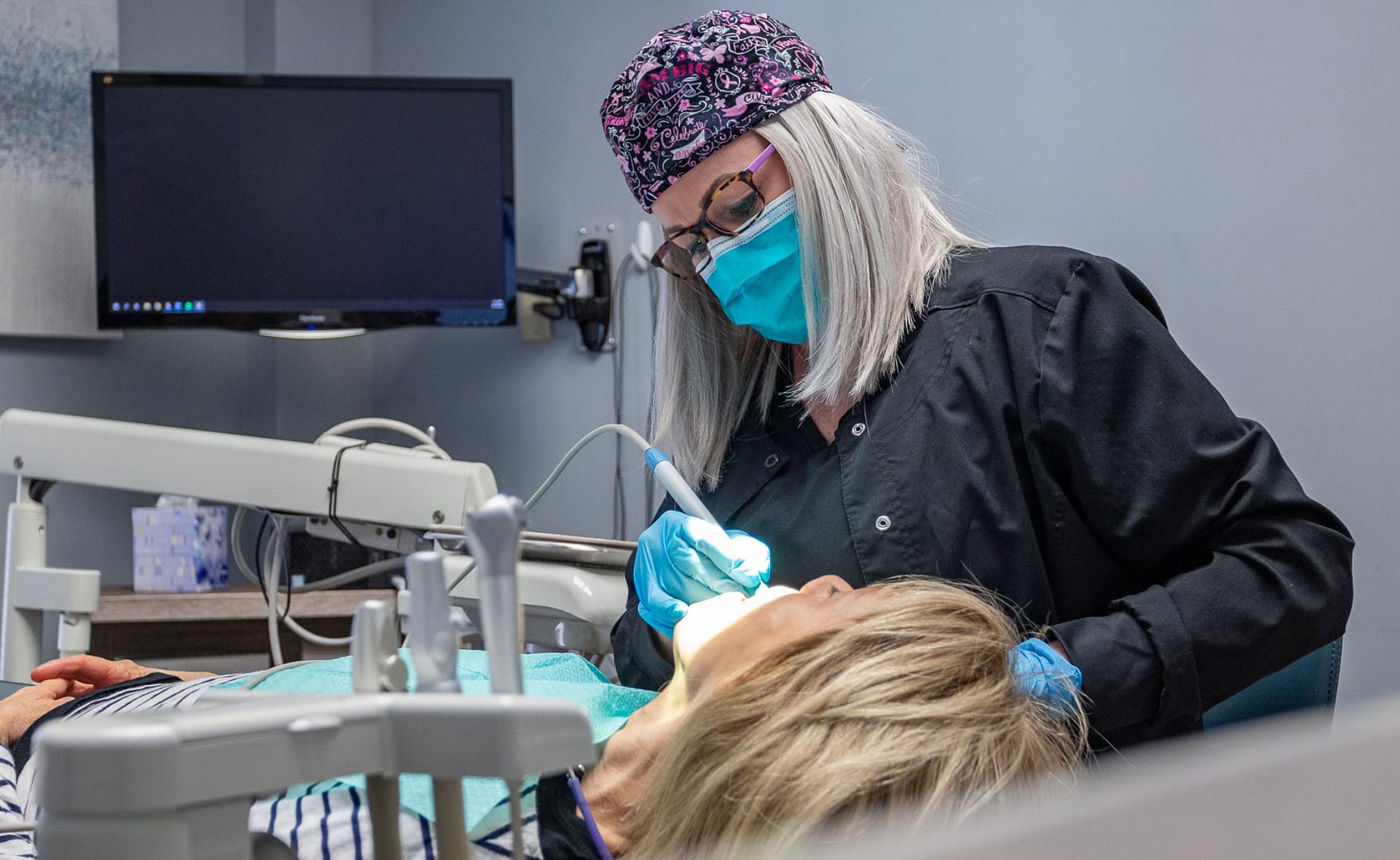 dental team member performing hygiene procedure on patient in dental chair