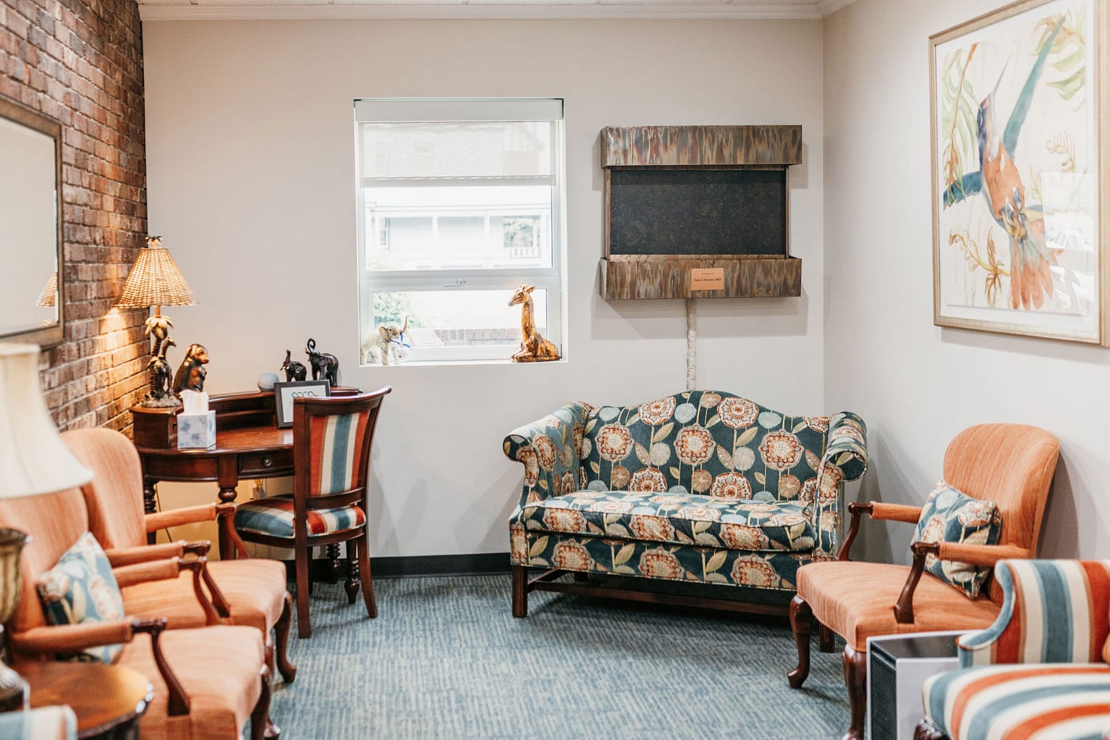 reception area with floral settee, orange chairs, and striped chairs