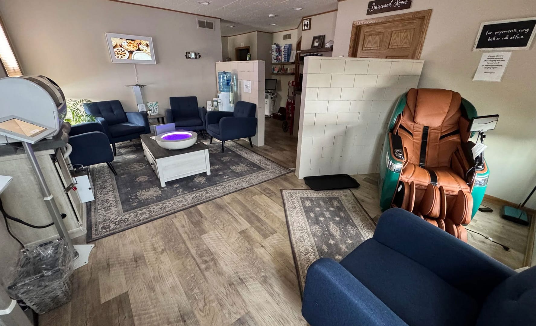 reception area with massage chair, blue chairs for seating, rugs on wood floors