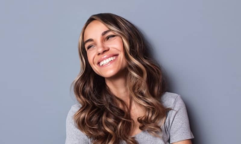 lady smiling against a drab blue wall