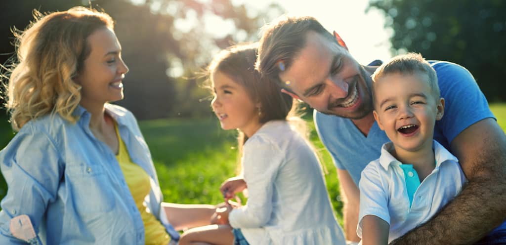 family of four with young son and young daughter sitting outside and smiling